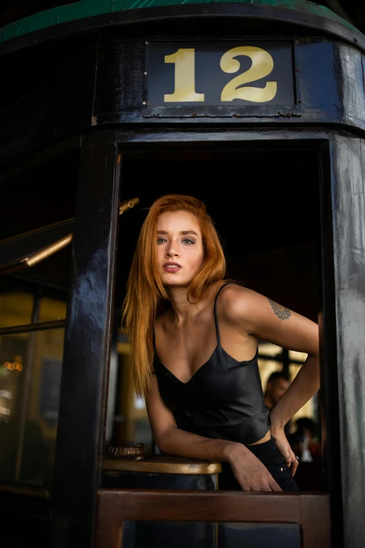 a woman standing in the doorway of a train car, inspired by Peter Lindbergh, pexels contest winner, photorealism, redhead girl, wearing black camisole outfit, at the counter, woman in streetwear