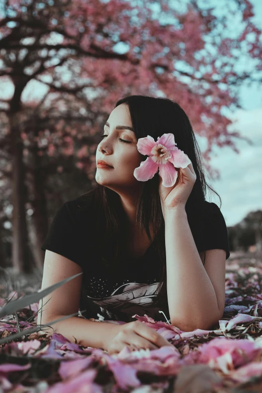 a woman laying on the ground with a flower in her hand, pexels contest winner, profile image, avatar image, flowers and trees, pink