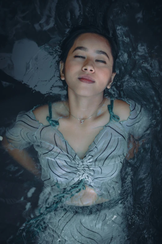 a woman floating in a body of water, an album cover, inspired by Yu Zhiding, trending on pexels, actress, full frame image, sink, looking down