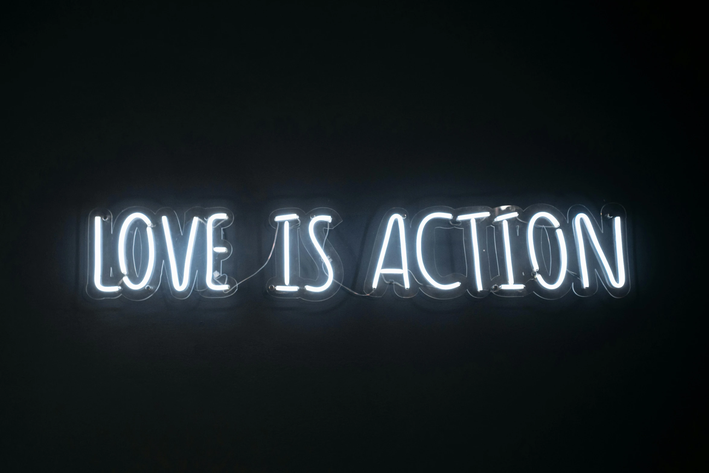 a neon sign that says love is action, pexels, in white lettering, y2k, daniel mirante, black