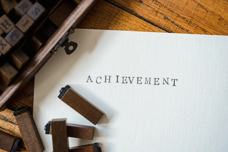 a piece of paper sitting on top of a wooden table, by Jacob Toorenvliet, pexels contest winner, academic art, rubber stamp, monumental achievement, written in a neat, aaaa achievement collection