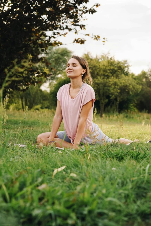 a woman sitting on top of a lush green field, doing splits and stretching, pink, midsommar, grey