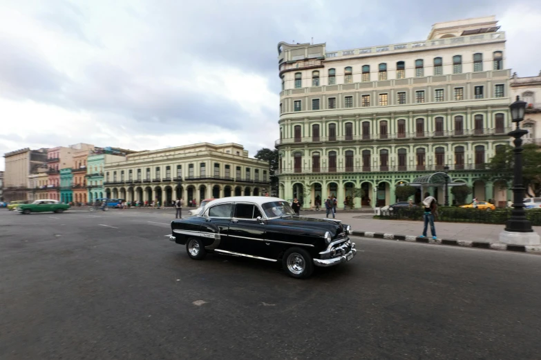 a black car driving down a street next to tall buildings, royal palace, conde nast traveler photo, square, 15081959 21121991 01012000 4k