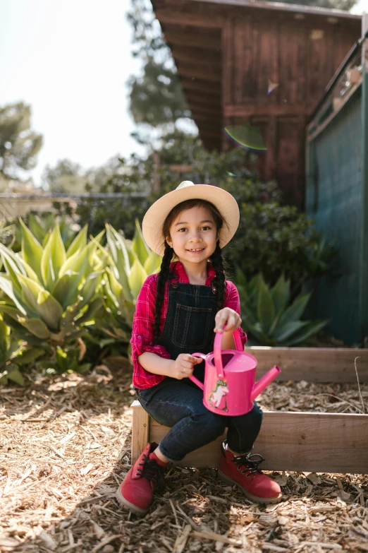 a little girl holding a pink watering can, by Jessie Algie, pexels contest winner, mai anh tran, wearing farm clothes, high resolution product photo, hero shot