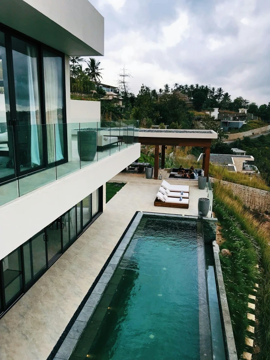 an aerial view of a house with a swimming pool, by Robbie Trevino, in the hillside, instagram story, on a cloudy day, built around ocean