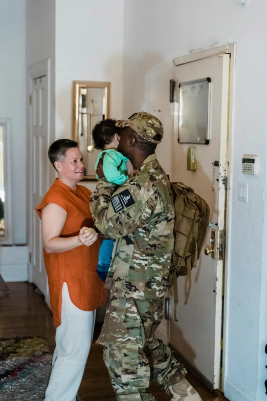 a woman in an orange shirt standing next to a soldier, by Kristin Nelson, pexels contest winner, hung above the door, maternal, nyc, military vest