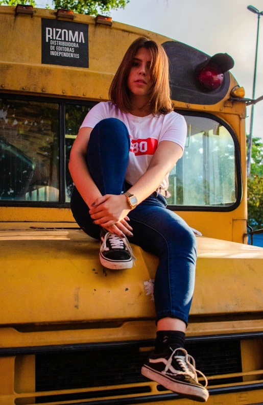 a woman sitting on top of a yellow school bus, an album cover, inspired by Elsa Bleda, trending on pexels, jeans and t shirt, girl wearing uniform, low quality photo, gopro photo