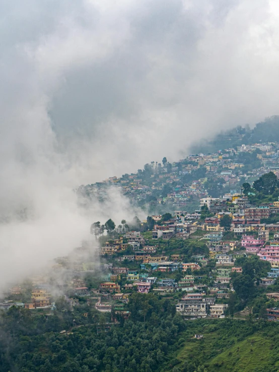 a group of buildings sitting on top of a lush green hillside, pexels contest winner, sumatraism, colored fog, during snowfall, hindu, panoramic