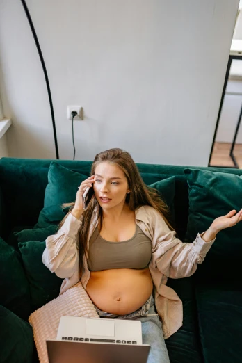 a pregnant woman sitting on a couch talking on a cell phone, by Sebastian Vrancx, trending on pexels, happening, wearing a sexy cropped top, green and brown clothes, surprised, taken in 2 0 2 0