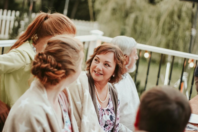 a group of people sitting around a table, by Emma Andijewska, pexels contest winner, happening, woman with braided brown hair, family friendly, wedding, at the terrace