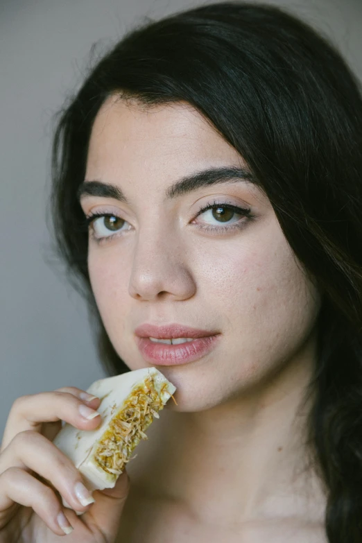 a woman holding a piece of food in her hand, portrait sophie mudd, wearing wheat yellow gauze, 1 / 4 headshot, sandwich