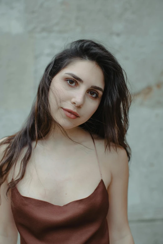 a woman in a brown dress posing for a picture, inspired by Elsa Bleda, trending on pexels, pale-skinned persian girl, centered shoulders up view, lovingly looking at camera, julia sarda