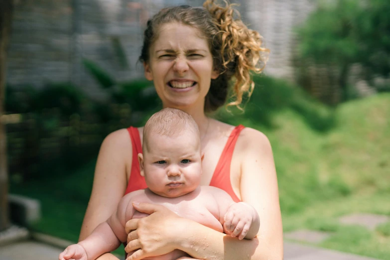 a woman holding a baby in her arms, a portrait, pexels contest winner, happening, sweaty insane, thumbnail, no cropping, with a pouting smile