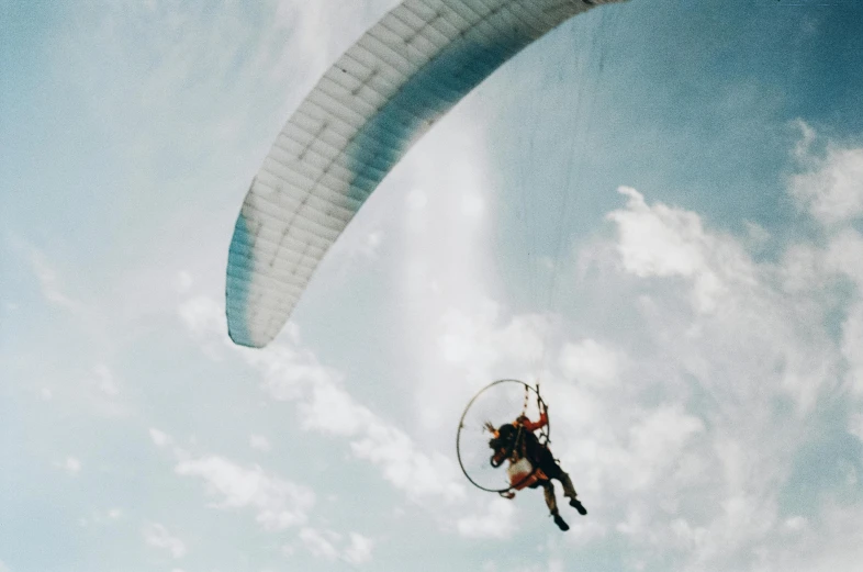 a man flying through the air while holding onto a parachute, by Joe Bowler, pexels contest winner, photo taken on fujifilm superia, instagram story, harness, half turned around