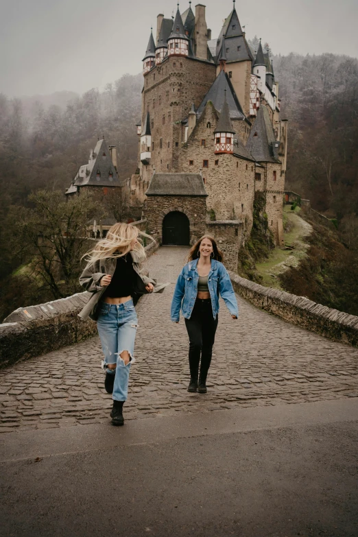 two women walking across a bridge in front of a castle, pexels contest winner, renaissance, wearing a jeans jackets, college girls, gif