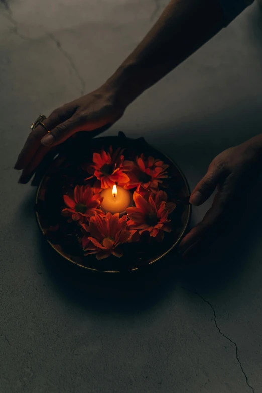 a person holding a lit candle in a bowl, an album cover, inspired by Elsa Bleda, pexels contest winner, hurufiyya, hinduism, glowing flowers, glowing red, tranquil