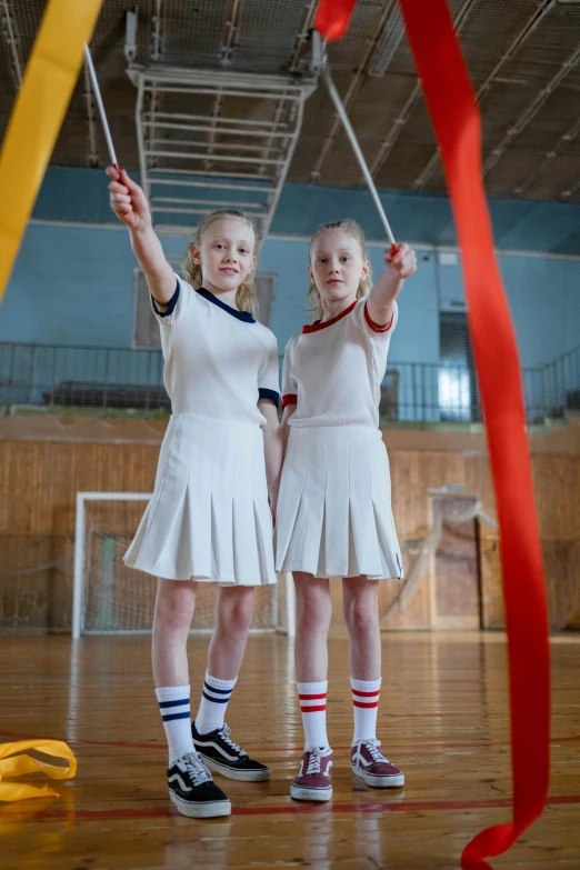 a couple of girls standing next to each other on a basketball court, a portrait, by Anna Findlay, unsplash, ribbons, dressed as schoolgirl, ( ( theatrical ) ), swings