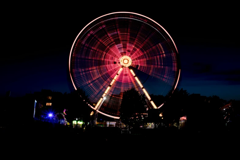 a ferris wheel is lit up at night, by Thomas Häfner, pexels contest winner, kinetic art, red rim light, city park, lightpainting, pink