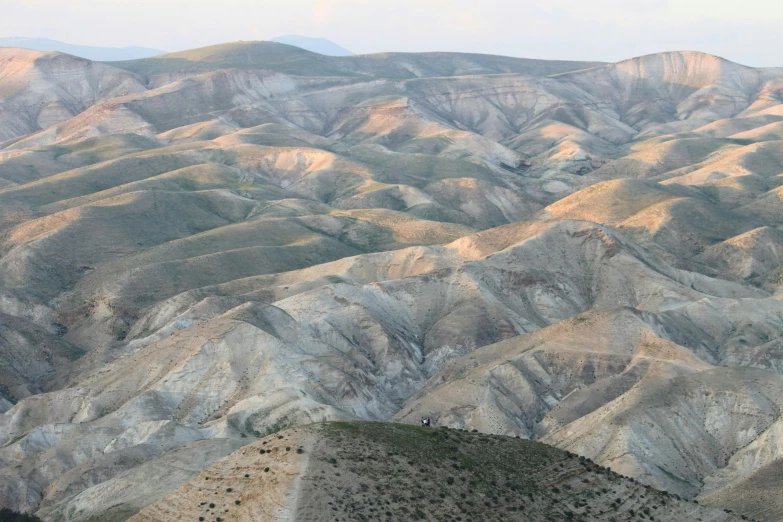 a group of people standing on top of a mountain, an album cover, by Edward Avedisian, trending on unsplash, israel, between sedimentary deposits, hills, zoomed out to show entire image