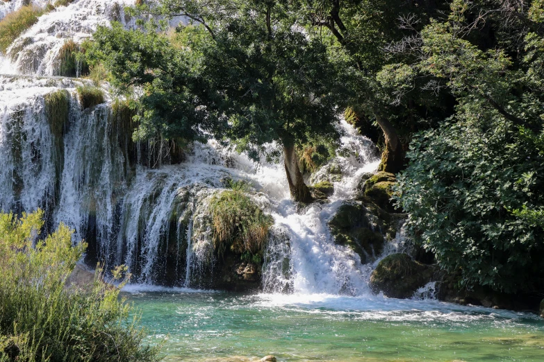 a waterfall in the middle of a lush green forest, by Mirko Rački, pexels contest winner, hurufiyya, white travertine terraces, fishing, 2000s photo