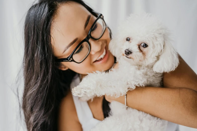 a woman holding a white dog in her arms, trending on pexels, wavy long black hair and glasses, manuka, asian female, multiple stories