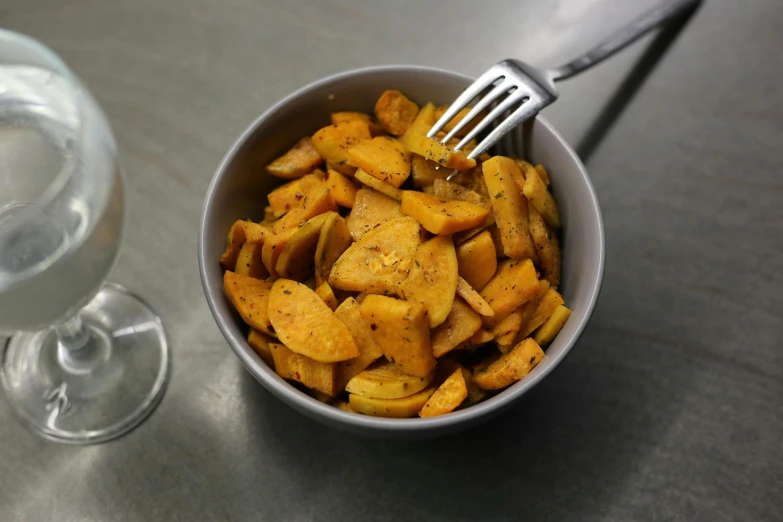 a bowl of food next to a glass of water, potatoes, thumbnail, pumpkin, spoon placed