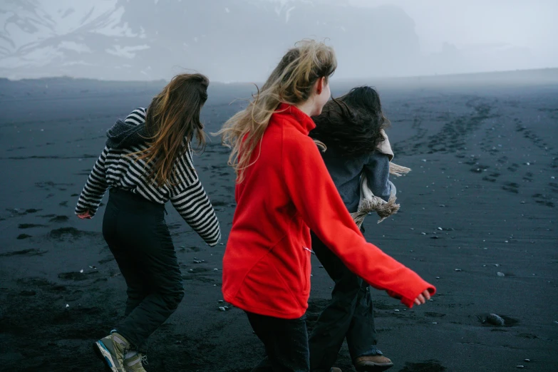 a group of people walking across a beach, by Louisa Matthíasdóttir, pexels contest winner, wearing a scarlet hoodie, black sand, three women, background image