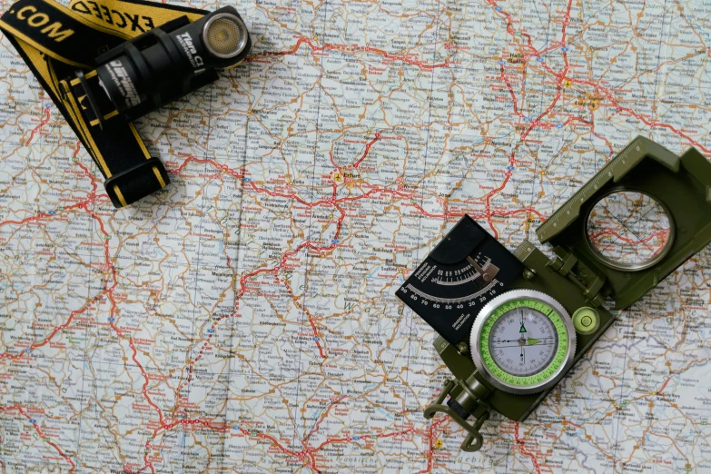 a green compass sitting on top of a map, by Adam Marczyński, pexels, military equipment, highways, touring, flat lay