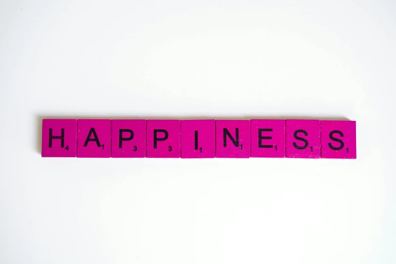 a pink wooden block with the word happiness written on it, by Caro Niederer, pexels, happening, squares, set against a white background, 🌻🎹🎼