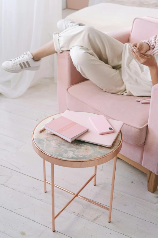 a woman laying on top of a pink couch, a picture, by Maud Naftel, trending on pexels, marble table, diary on her hand, white and light-pink outfit, sitting on chair