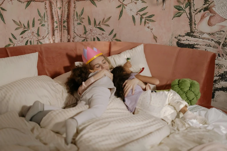 a couple of kids laying on top of a bed, inspired by Elsa Beskow, trending on pexels, woman holding another woman, at a birthday party, still image from tv series, sleeping beauty