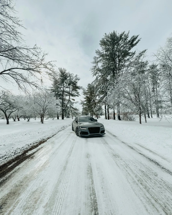 a car driving down a snow covered road, with a park in the background, posing