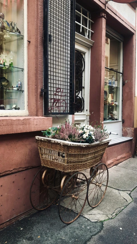 a basket that is sitting on the side of a building, pexels contest winner, renaissance, flower shop scene, chariot, vintage inspired, square