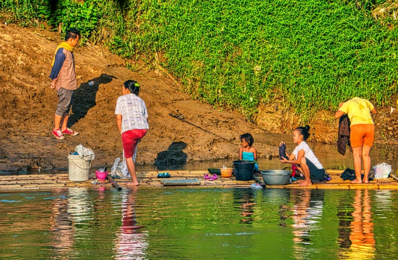 a group of people standing next to a body of water, by Sven Erixson, pexels contest winner, process art, laos, people on a picnic, warm sunshine, family friendly