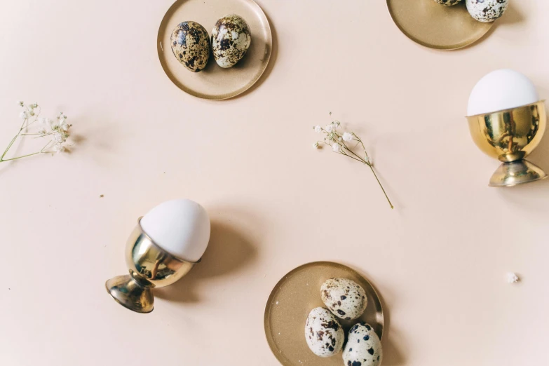 a white egg sitting on top of a gold plate, a still life, by Emma Andijewska, trending on unsplash, background image, miscellaneous objects, brown and pink color scheme, multiple stories