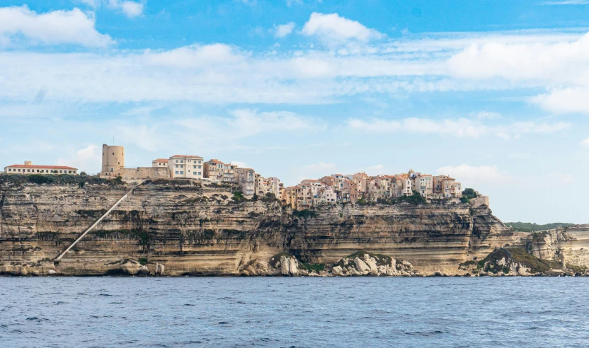 a large body of water next to a cliff, a matte painting, pexels contest winner, les nabis, mediterranean city, traditional corsican, geological strata, conde nast traveler photo