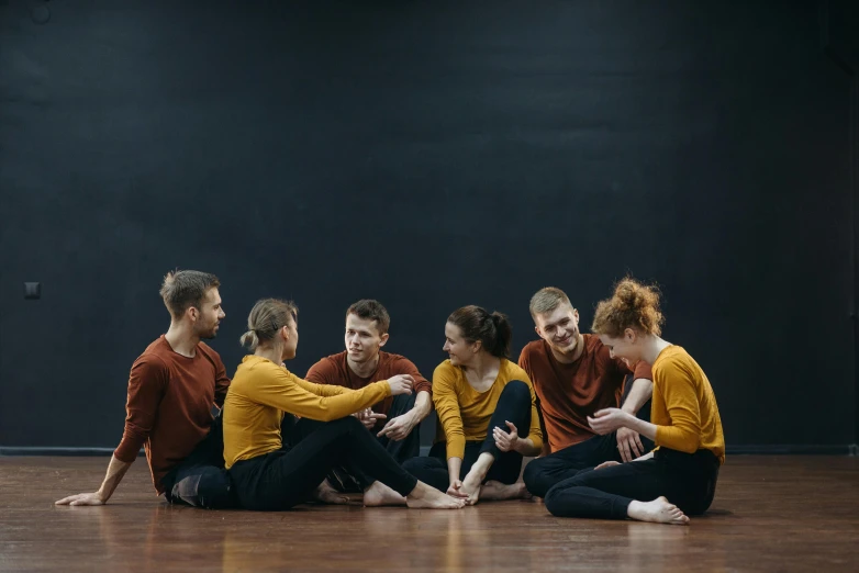 a group of people sitting on top of a wooden floor, a portrait, by Emma Andijewska, unsplash, antipodeans, choreographed, ochre, profile image, group of seven