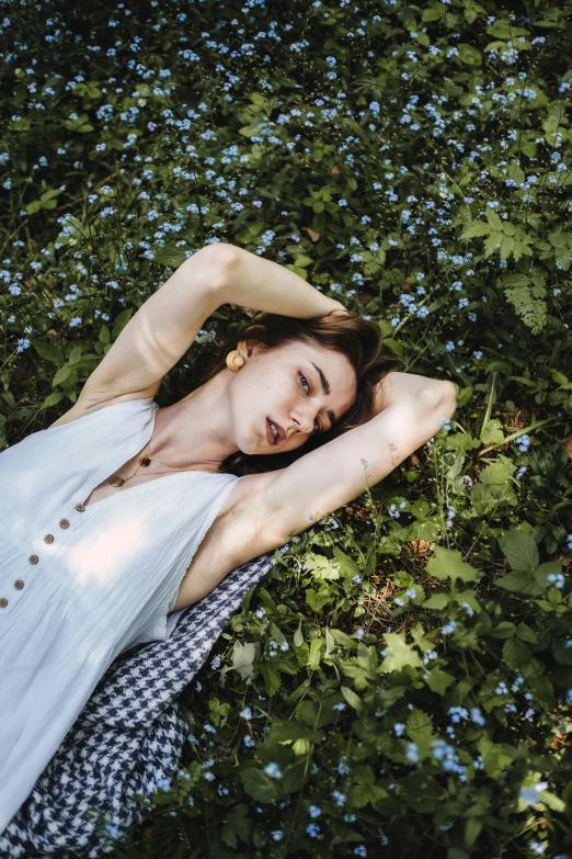 a woman laying on top of a lush green field, inspired by Elsa Bleda, pexels contest winner, sleepy fashion model face, al fresco, high angle shot, androgynous person