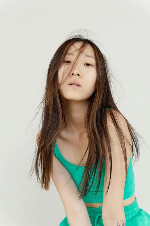 a woman in a green top and shorts, an album cover, inspired by Fei Danxu, trending on pexels, upward flowing long hair, at a fashion shoot, thin aged 2 5, jingna zhang