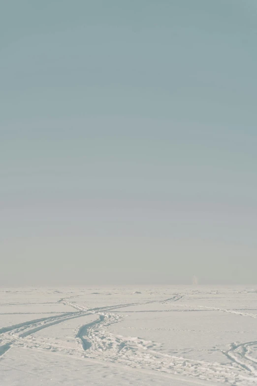 a man riding skis down a snow covered slope, an album cover, unsplash, conceptual art, desolate arctic landscape, ffffound, norilsk, distant photo