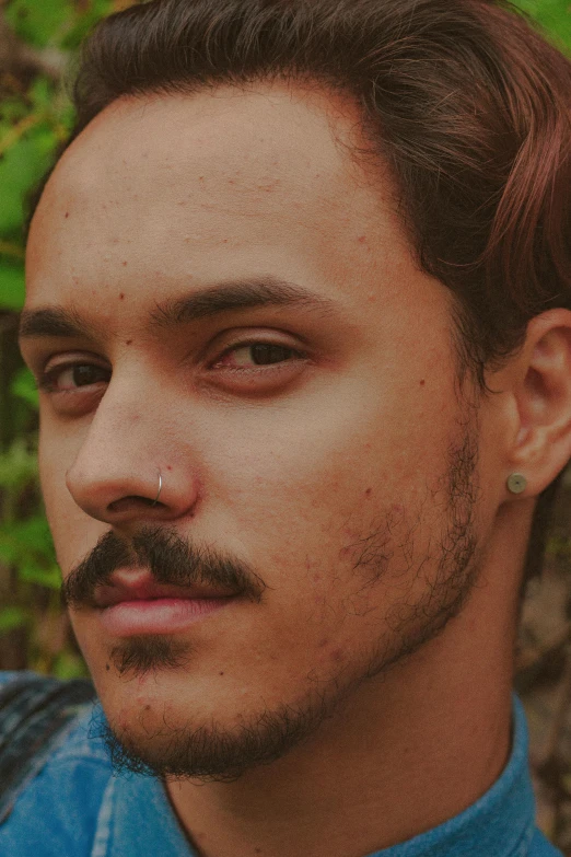 a man with a mustache wearing a blue shirt, an album cover, inspired by Elsa Bleda, trending on pexels, antipodeans, androgynous face, mixed race, septum piercing, headshot profile picture