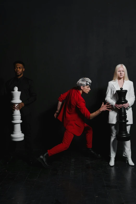 a group of people playing a game of chess, an album cover, by Lisa Milroy, international gothic, crazy white hair, red and black suit, an epic non - binary model, pose 4 of 1 6