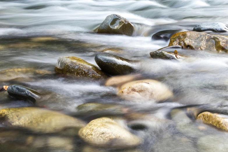 a group of rocks sitting on top of a river, unsplash, medium format. soft light, rushing water, ((rocks))