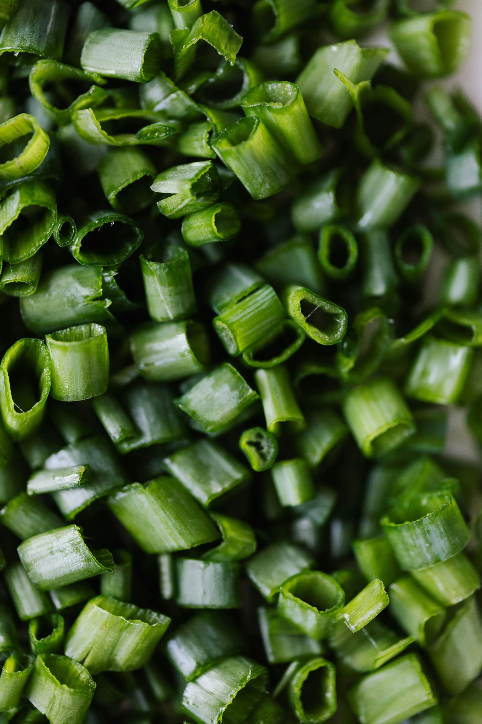 a pile of chopped green onions on a cutting board, by Anne Savage, unsplash, intricate detail, twisting leaves, pasta, beans