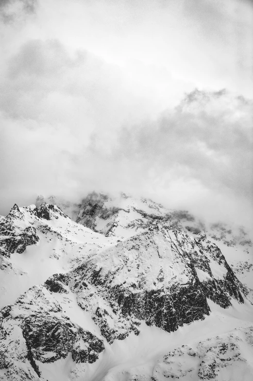 a black and white photo of a snow covered mountain, a black and white photo, by Matthias Weischer, made of mist, cloudy day, alp, covered in