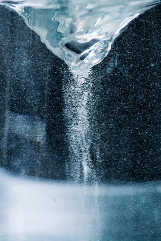 a glass filled with water sitting on top of a counter, by Doug Ohlson, trending on unsplash, process art, sugar snow, high angle close up shot, bubbling geysers, made of liquid metal