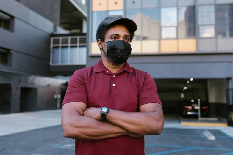 a man wearing a face mask standing in a parking lot, a portrait, maroon, square, dark-skinned, professional image