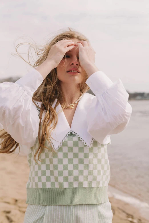 a woman standing on top of a sandy beach, inspired by Anita Malfatti, trending on pexels, renaissance, cute checkerboard sundress, sea - green and white clothes, big collar, wearing a white sweater