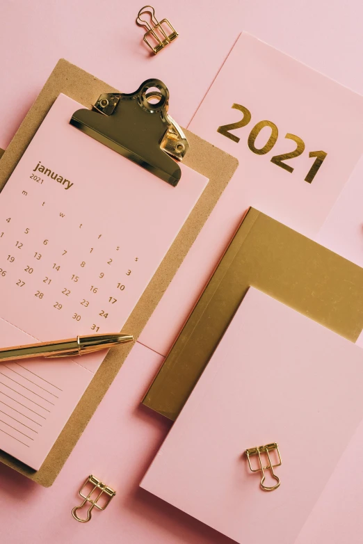 a calendar sitting on top of a desk next to a pen, by Julia Pishtar, happening, pink and gold, thumbnail, new years eve, center of image