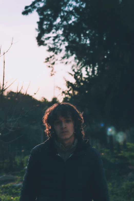 a man standing in the middle of a field, an album cover, unsplash, renaissance, soft evening lighting, his hair is messy and unkempt, in a garden, ((sunset))